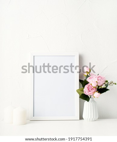 Mock up white frame on the wall with peonies and white candles