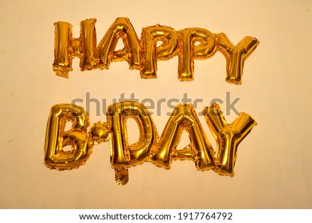 Golden HAPPY BIRTHDAY words made of inflatable balloons hanging on a wall. 