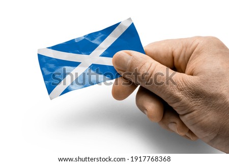 Hand holding a card with a national flag the Scotland