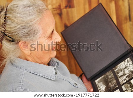 Old woman with album on wooden background, closeup.