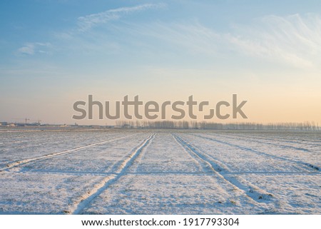 A farm at the rural area in snow time, at sunset.