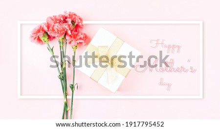 Three beautiful red carnations against with gift a pink background. Photo caption happy mother's day. Greeting card.