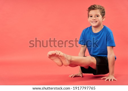 Cheerful boy doing exercise against red background