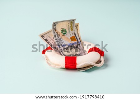 A lifebuoy with banknotes lie on a blue background, the concept of assistance and security in finance Royalty-Free Stock Photo #1917798410