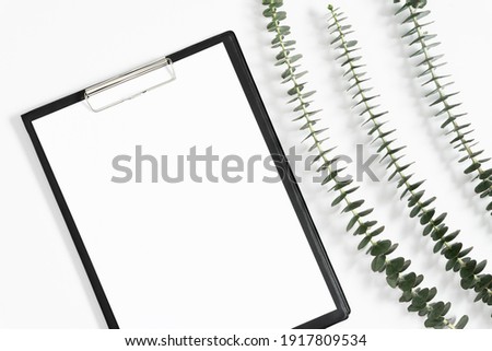 Black clipboard mockup with eucalyptus on white background. Flat lay, top view, copy space