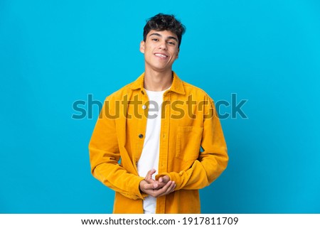 Young man over isolated blue background laughing