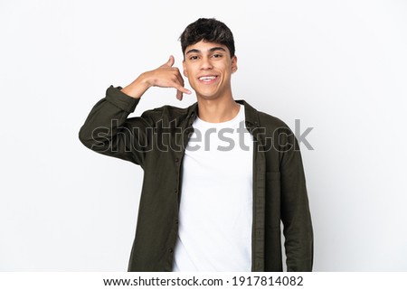 Young man over isolated white background making phone gesture. Call me back sign