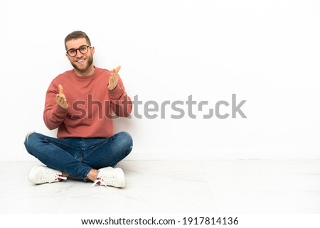 Young handsome man sitting on the floor applauding after presentation in a conference