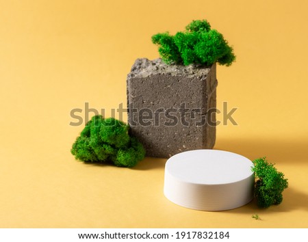 abstract composition with white podium, natural stone and moss on yellow background. Minimal modern product display
