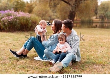 Charming young family having fun outdoor with little kids in park during sunset.