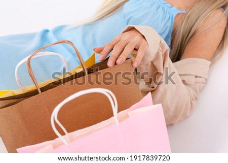 Fashionable portrait of a slender blonde with long hair in a light blue dress and a corduroy shirt with a shopping bag in the studio on a white background
