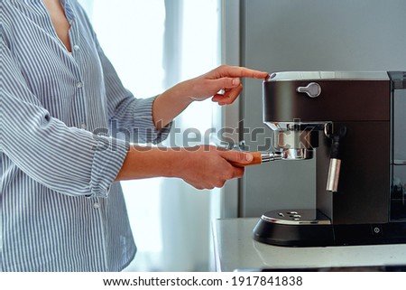 Female hands holding portafilter and making fresh aromatic coffee at home using a modern coffee maker  Royalty-Free Stock Photo #1917841838