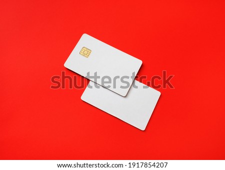Photo of two blank credit cards on red paper background. White bank cards.
