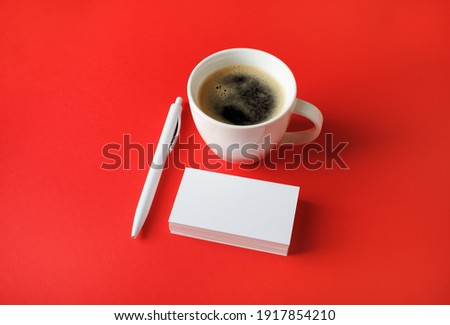 Corporate identity template. Blank business cards, coffee cup and pen on red paper background.