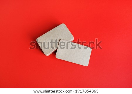 Photo of blank kraft business cards on red paper background. Mockup for branding identity. Blank corporate identity template.