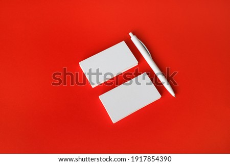 Photo of blank white business cards and pen on red paper background. Copy space for text.