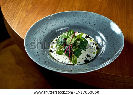 Healthy and dietary food - Brussels sprouts stewed in a creamy sauce with spinach served in a blue plate on a wooden background. View from above