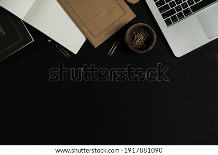 Flatlay of laptop computer, craft notebook sheet, clips in wooden bowl on black background. Home office desk workspace. Business, work template. Flat lay, top view.