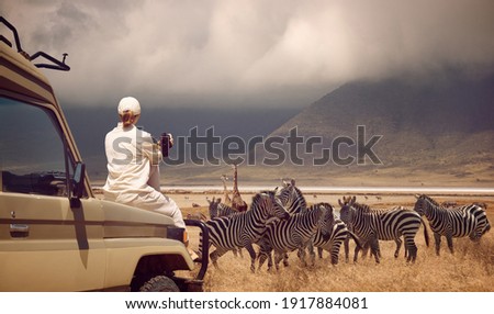 Woman traveler on safari-tour in Africa, traveling by car in Tanzania, watching wild animals and birds in the National park Ngorongoro. Royalty-Free Stock Photo #1917884081