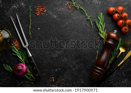 Black stone kitchen background with spices, herbs and kitchen utensils. Free space for text. Top view. Rustic style.