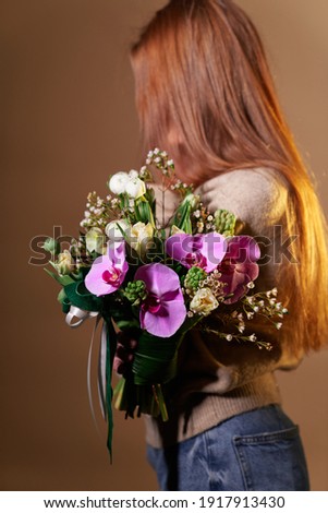 Beautiful woman in beige sweater and jeans with flower bouquet, no face, spring theme. Mother's Day, St. Valentine's day or International Woman's Day concept
