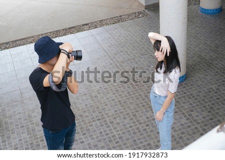 Male photographer take a photo of teenage model girl at the building.