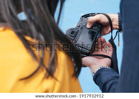 Cropped image of camera while photographer and model look at the photo they take.