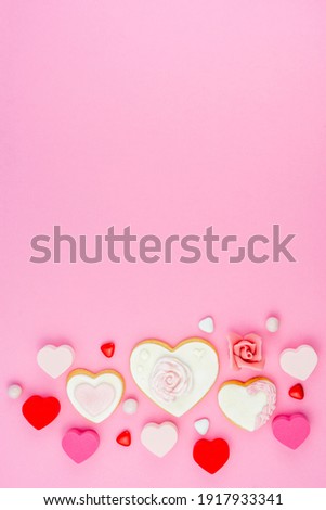 Decorated heart shaped and rose cookies on pink background, flat lay with space for text. Marshmallow, Biscuit and Candy sweets. Valentine's day concept. Blurred bokeh light bubble background