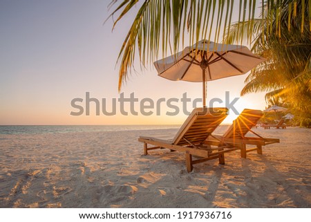 Beautiful tropical sunset scenery, two sun beds, loungers, umbrella under palm tree. White sand, sea view with horizon, colorful twilight sky, calmness and relaxation. Inspirational beach resort hotel Royalty-Free Stock Photo #1917936716