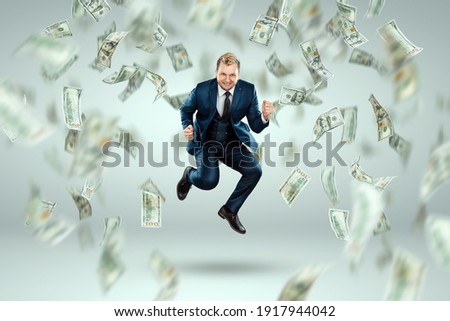 A man in a business suit jumps for joy against the background of falling dollars, rain of money. Business concept, bookmaker, sports betting, investment, passive income
