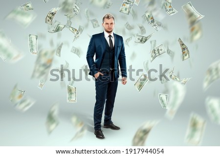 A man in a business suit stands against the background of falling dollars, banknotes are falling from the sky. Business concept, bookmaker, sports betting, investment, passive income