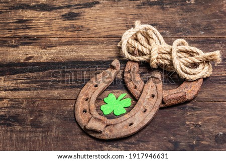 Badly worn horseshoes, rope, and felt clover leaf. Good luck symbol, St.Patrick's day concept. Vintage wooden boards background