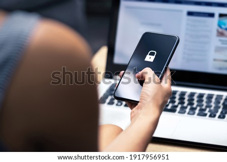 Phishing, mobile phone hacker or cyber scam concept. Password and login pass code in smartphone. Online security threat and fraud. Female scammer with cellphone and laptop. Bank account security. Royalty-Free Stock Photo #1917956951