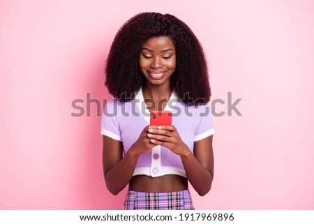 Portrait of pretty focused cheerful wavy-haired girl using device browsing news media isolated over pink pastel color background