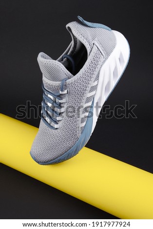 Gray sport shoes for running with yellow tube on dark background. Concept healthy lifestyle, sport and fitness. Color 2021 year. Fashion cushion Sneakers.