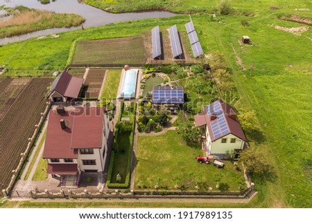 Aerial view of a private house in summer with blue solar photo voltaic panels on roof top and in the yard.