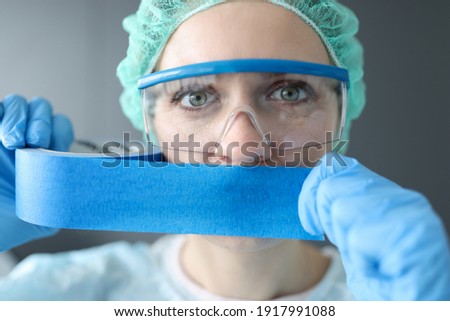 Woman doctor sealing her mouth with blue tape. Medical secrecy concept Royalty-Free Stock Photo #1917991088