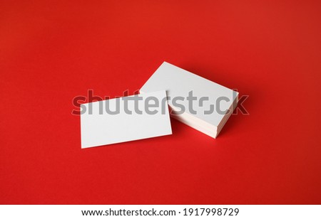 Photo of blank business cards on red paper background. Template for branding identity.