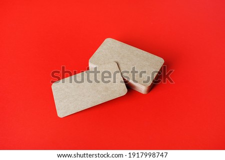 Photo of blank kraft business cards on red paper background. Template for ID.
