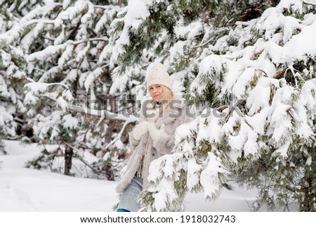 Beautiful young scandinavian caucasian woman on a walk in the forest in winter, among the snowy pine trees
