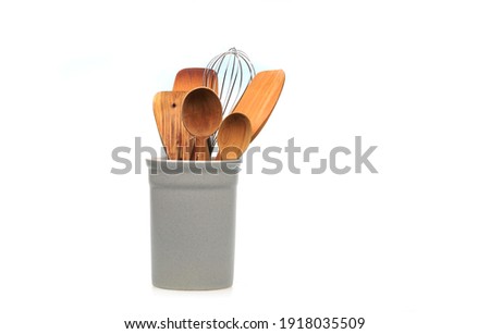 Wooden utensils for cooking are in a white glass. Kitchen spoons, scoops, forks isolated on white background. Scandinavian style in the interior of the kitchen. Royalty-Free Stock Photo #1918035509