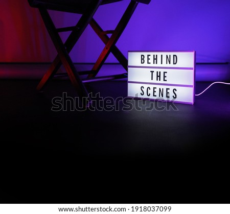 Behind the scenes letterboard text on Lightbox or Cinema Light box. Movie clapperboard megaphone and director chair beside. Background LED color change. static camera in video production studio.