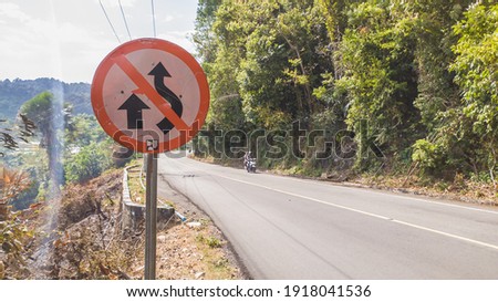 Road signs "Do not overtake other vehicles" against the background of the road in the mountains, Aceh Indonesia