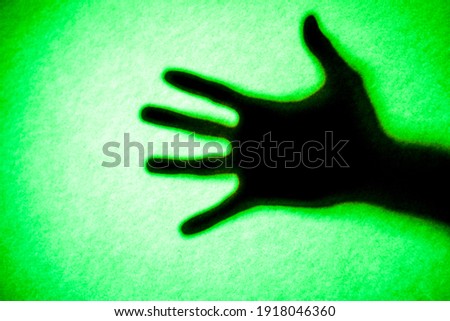 Mans hand as actor of shadow theatre. Hand's shadow as figure of Shadow hands of the Man behind frosted glass. Blurry hand abstraction. Halloween background. Black and white picture