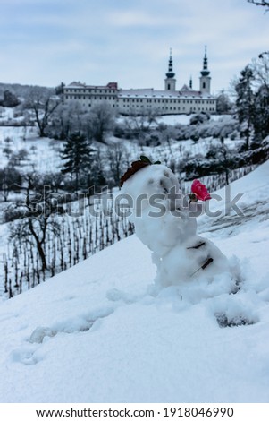 Snowman and Strahov Monastery with church of the Assumption of the Blessed Virgin Mary in background, Prague, Czech Republic. Prague winter panorama.Winter fun in the city.Amazing European cityscape