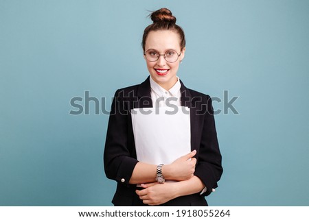 Girl with red lips in glasses working in the office while standing with a pile of papers in her hands standing on a blue background. Office affairs