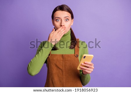 Portrait of nice worried girl using gadget closing mouth keeping silence isolated over bright violet color background