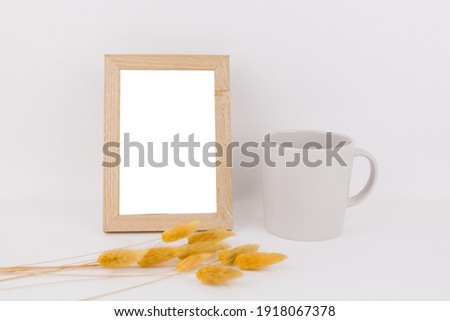 a photo frame on the table with a cup and spikelet