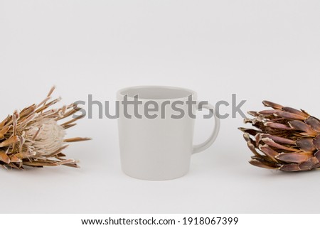 a gray cup with dried flowers on the table
