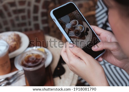 A girl take a picture of coffee and cake by smartphone in cafe